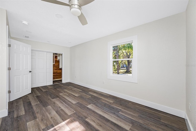 unfurnished bedroom featuring dark hardwood / wood-style flooring, ceiling fan, and a closet