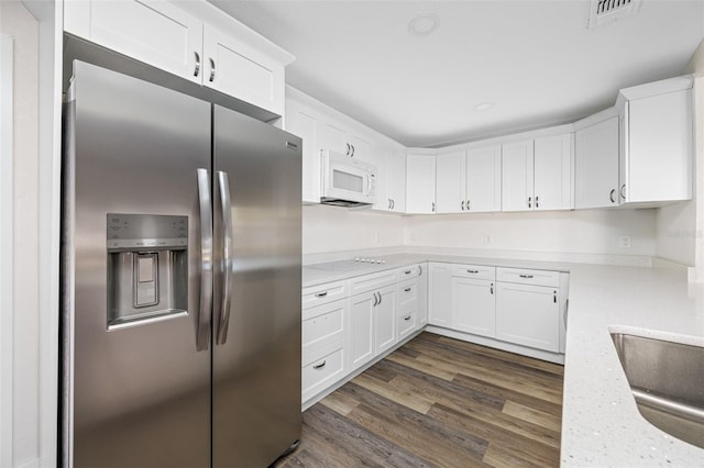 kitchen with sink, dark wood-type flooring, white cabinetry, stainless steel refrigerator with ice dispenser, and light stone counters