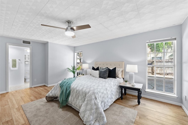 bedroom with light wood-type flooring, ensuite bath, and ceiling fan