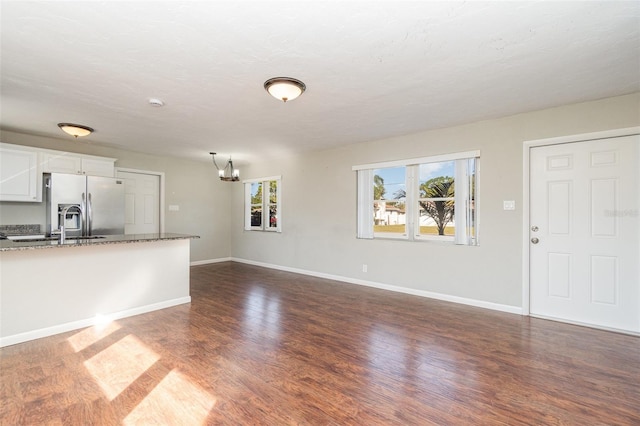 unfurnished living room featuring dark hardwood / wood-style floors and an inviting chandelier