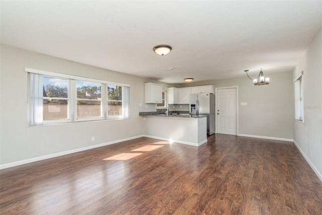 unfurnished living room with sink, dark wood-type flooring, and a notable chandelier