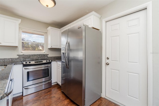 kitchen with white cabinets, dark hardwood / wood-style floors, appliances with stainless steel finishes, and dark stone counters