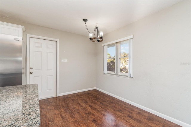 unfurnished dining area with dark hardwood / wood-style floors and a notable chandelier