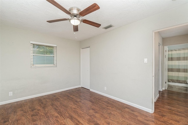 unfurnished room featuring a textured ceiling, ceiling fan, and dark wood-type flooring