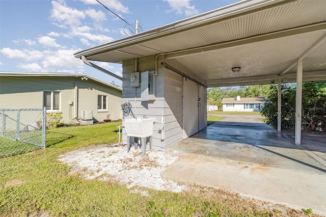 exterior space featuring a lawn, sink, cooling unit, and a carport