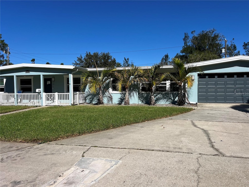 single story home with a porch, a garage, and a front yard