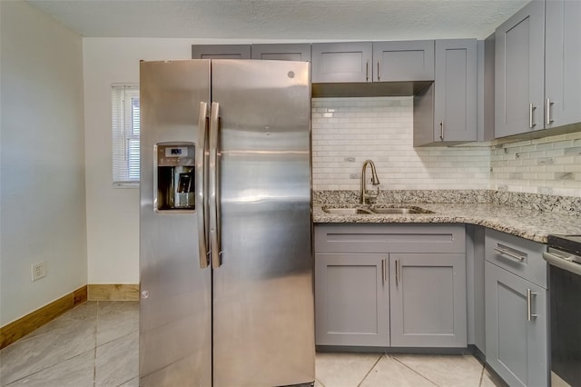 kitchen with light stone countertops, appliances with stainless steel finishes, decorative backsplash, sink, and gray cabinets