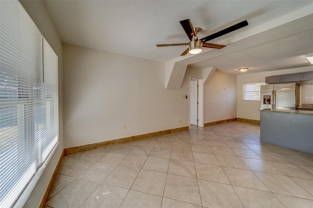 unfurnished living room with ceiling fan, light tile patterned floors, and a textured ceiling