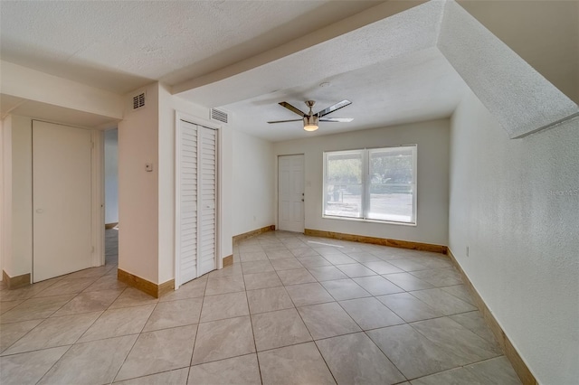 unfurnished room featuring ceiling fan, light tile patterned floors, and a textured ceiling