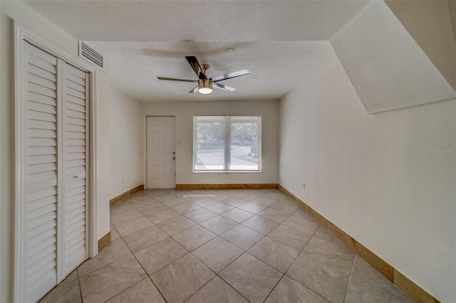 interior space with ceiling fan, a closet, light tile patterned floors, and a textured ceiling