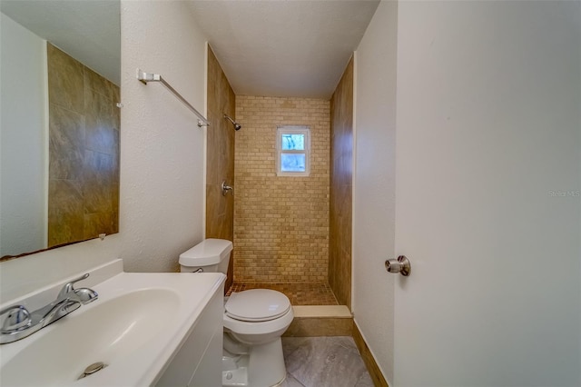 bathroom with tile patterned flooring, tiled shower, toilet, and a textured ceiling