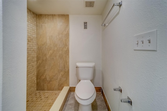 bathroom with a tile shower, tile patterned floors, and toilet