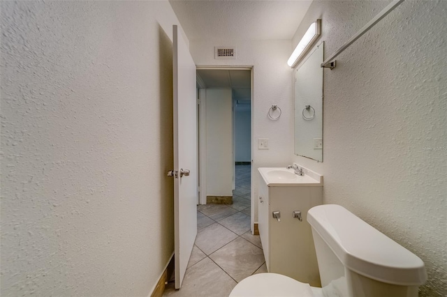 bathroom featuring tile patterned flooring, vanity, toilet, and a textured ceiling