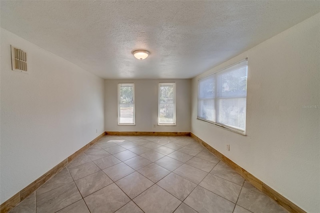 spare room with light tile patterned floors and a textured ceiling