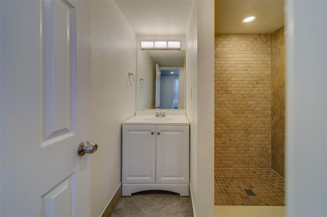 bathroom with a tile shower, tile patterned flooring, and vanity