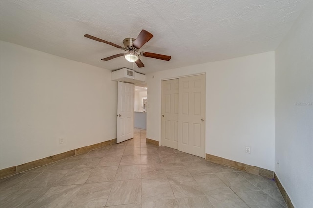 unfurnished bedroom featuring ceiling fan, a closet, light tile patterned floors, and a textured ceiling