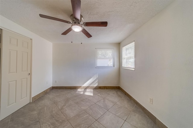 tiled empty room featuring ceiling fan and a textured ceiling