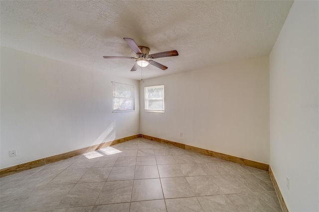 tiled empty room with ceiling fan and a textured ceiling