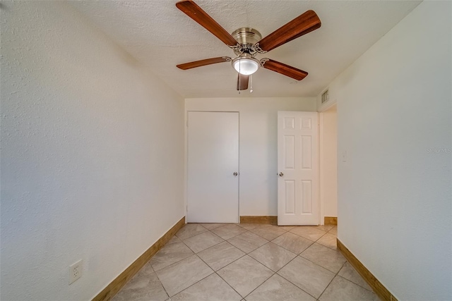 spare room featuring ceiling fan, light tile patterned floors, and a textured ceiling