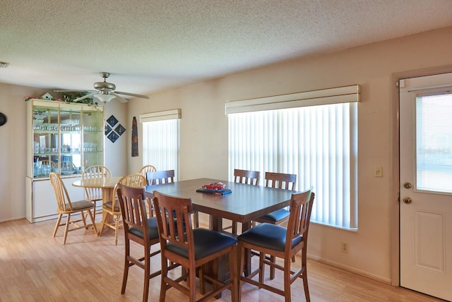 dining area featuring ceiling fan, light hardwood / wood-style floors, and a textured ceiling