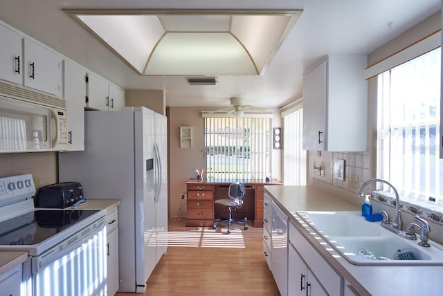 kitchen featuring a healthy amount of sunlight, white appliances, and white cabinetry