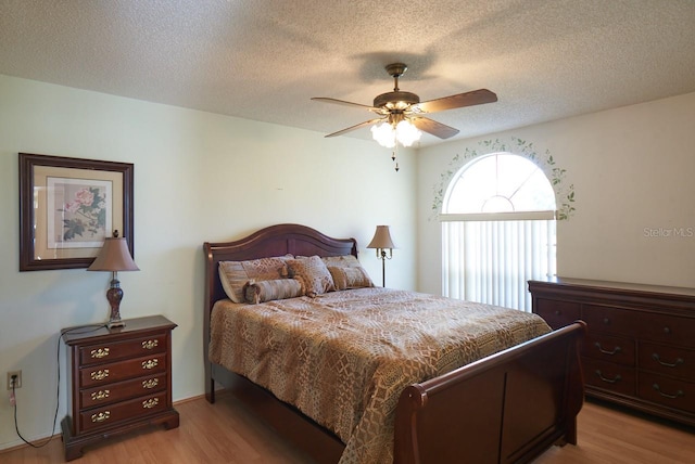 bedroom with ceiling fan, light hardwood / wood-style floors, and a textured ceiling