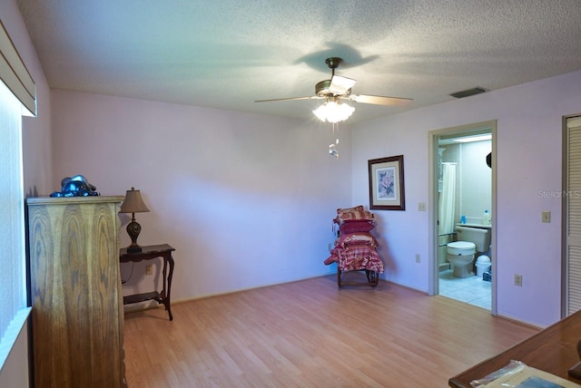 sitting room featuring ceiling fan, a textured ceiling, and light hardwood / wood-style flooring