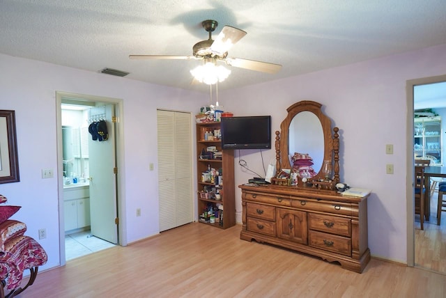 miscellaneous room featuring ceiling fan, light hardwood / wood-style floors, and a textured ceiling