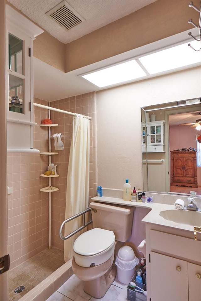 bathroom featuring tile patterned flooring, vanity, toilet, and walk in shower