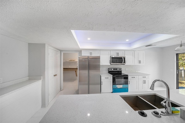 kitchen with a textured ceiling, white cabinetry, sink, a raised ceiling, and stainless steel appliances