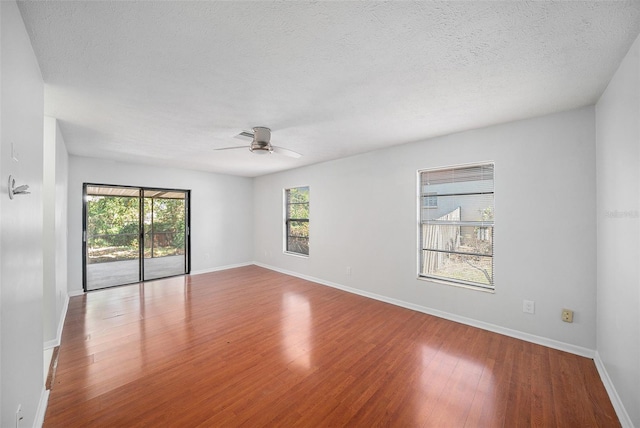 empty room featuring ceiling fan, light wood-type flooring, a textured ceiling, and a wealth of natural light