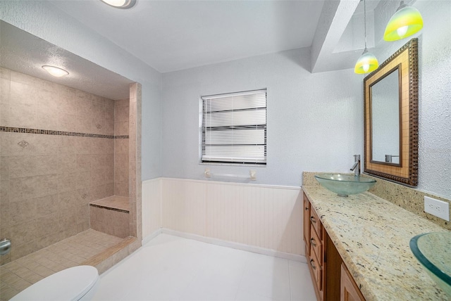 bathroom featuring wood walls, toilet, vanity, and a tile shower