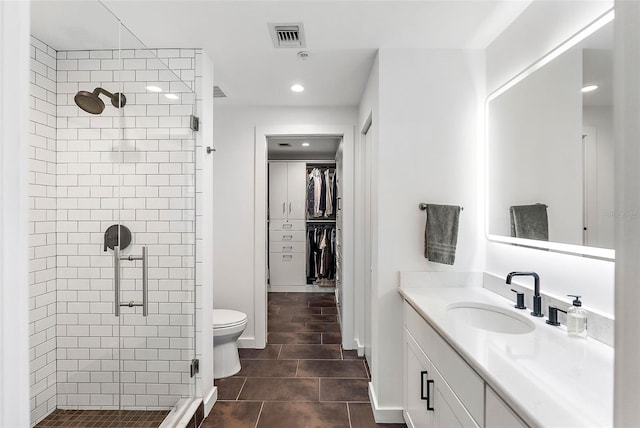 bathroom featuring toilet, a shower with shower door, and vanity