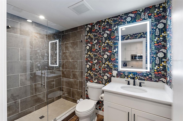 bathroom featuring toilet, decorative backsplash, a shower with shower door, and vanity