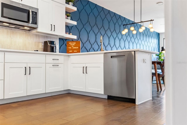 kitchen featuring hanging light fixtures, tasteful backsplash, stainless steel appliances, and white cabinetry