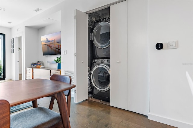 laundry room featuring dark hardwood / wood-style flooring and stacked washer / drying machine