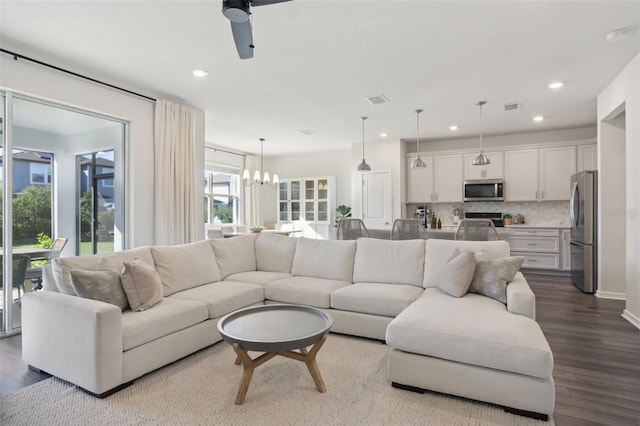 living room with hardwood / wood-style floors and ceiling fan with notable chandelier