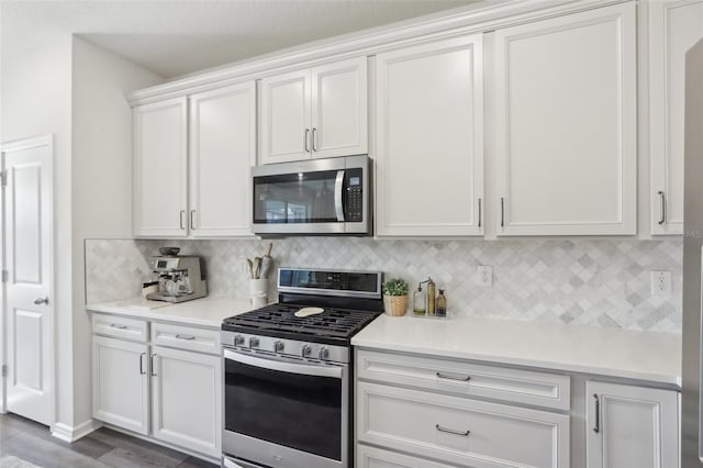 kitchen with backsplash, stainless steel appliances, white cabinetry, and dark wood-type flooring