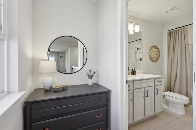 bathroom featuring tile patterned flooring, vanity, toilet, and walk in shower