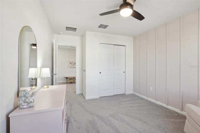 bedroom with ceiling fan, light colored carpet, and a closet