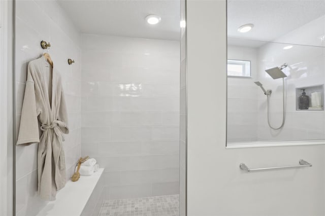 bathroom with a tile shower and a textured ceiling