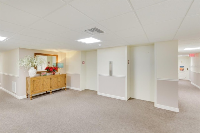 basement featuring a paneled ceiling and light carpet