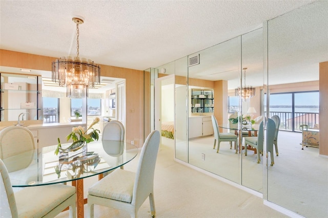 dining space with a chandelier, light carpet, a textured ceiling, and sink