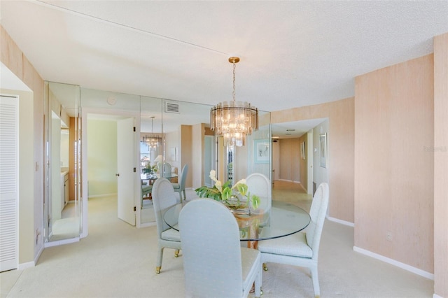 dining room featuring light colored carpet, a textured ceiling, and a chandelier