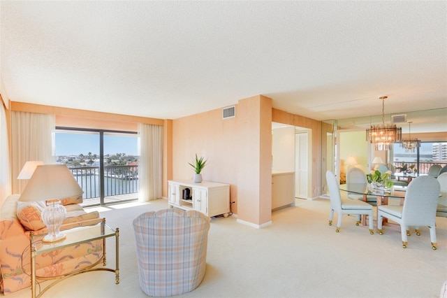 living room with light carpet, a textured ceiling, a water view, and a notable chandelier