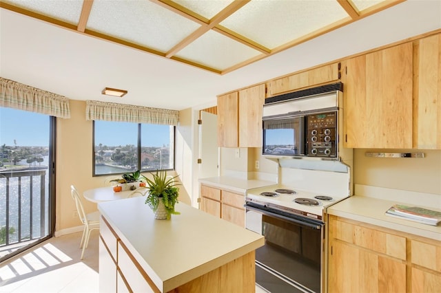 kitchen with light brown cabinets, a kitchen island, a healthy amount of sunlight, and white electric stove