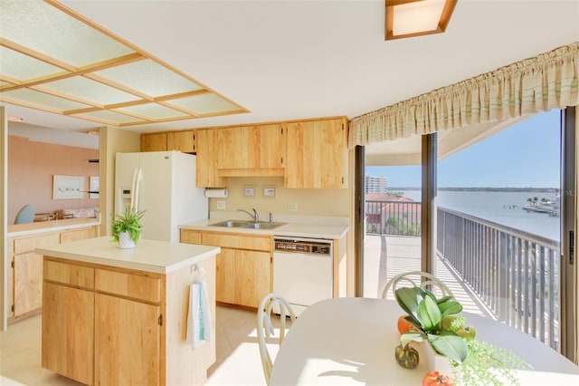 kitchen with white appliances, sink, light brown cabinets, a water view, and a center island