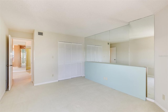 spare room with light carpet and a textured ceiling