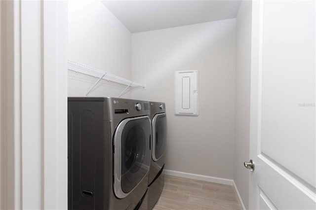 laundry area with washer and dryer, light wood-type flooring, and electric panel