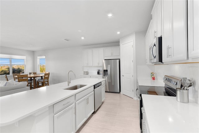 kitchen featuring white cabinets, sink, light hardwood / wood-style flooring, appliances with stainless steel finishes, and tasteful backsplash